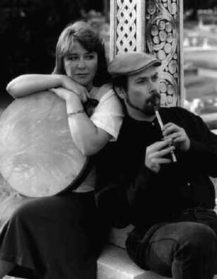 Bill playing Brenda an aire on the penny whistle while resting up against a Celtic cross.
